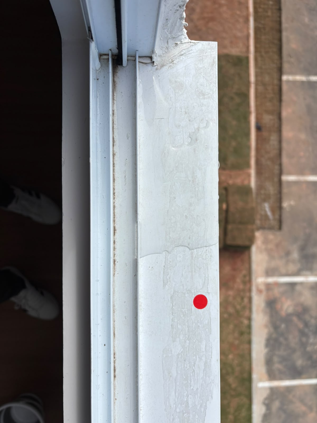 Detalhe do acabamento da esquadria de uma janela, sinalizado com adesivo vermelho
