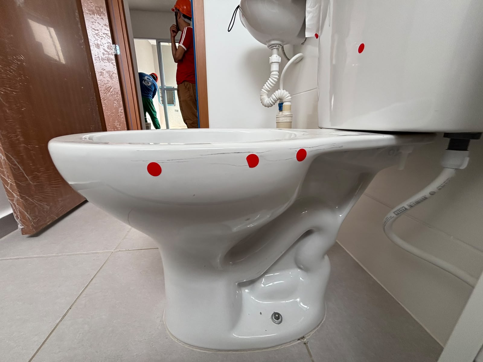 Louça sanitária com falhas sinalizadas por adesivos vermelhos durante a vistoria