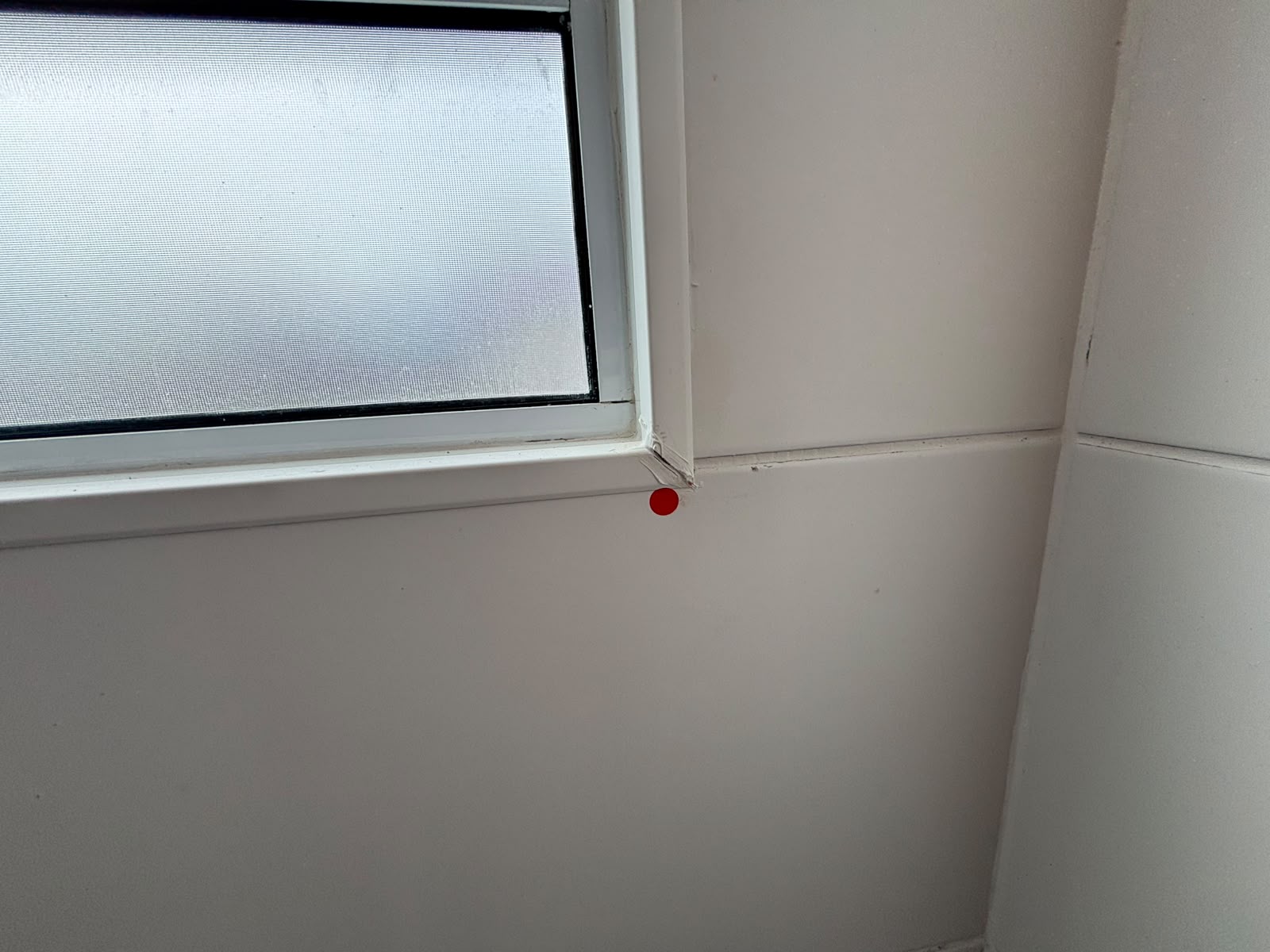 Detalhe do encontro entre a janela e o revestimento, sinalizado com adesivo vermelho